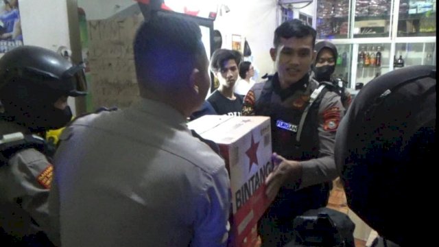 Polisi yang melakukan penggeledahan di ruko berkedok bengkel yang ternyata menjual miras. Foto: PORTALMEDIA/Reza