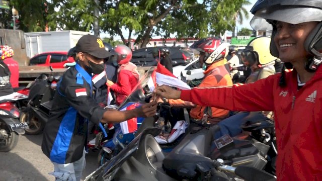 Mahasiswa Papua membagikan bendera merah putih  di Jalan Perintis Kemerdekaan, Kecamatan Tamalanrea, Kota Makassar, Sulawesi Selatan (Sulsel), tepat di hari kemerdekaan 17 Agustus 2022(PORTALMEDIA/REZA)