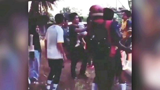 Potongan video yang memperlihatkan korban sedang menggendong anaknya sembari dipukuli pelaku. 