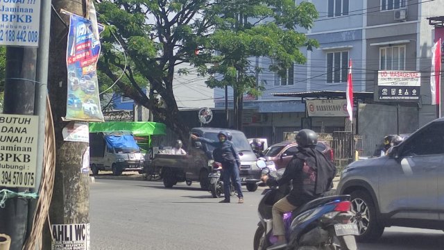 Aksi Pak Ogah di salah satu jalan di Kota Makassar. Foto: PORTALMEDIA/Al Fath