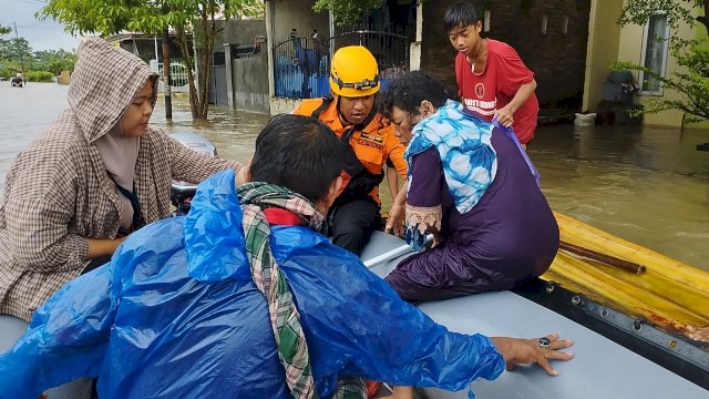Korban banjir yang ingin berpindah dari perahu batang pisang ke boat milik BPBD Makassar, Kamis (29/12/2022). Foto: Portalmedia.id/Firda