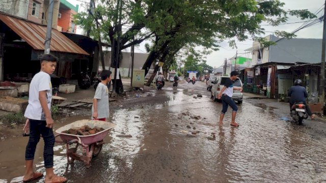Beberapa pemuda Kelurahan Romang Polong, Gowa bergotong royong menimbun lubang menganga di jalan Mustafa Dg Bunga. (Foto: Irham/portalmedia) 