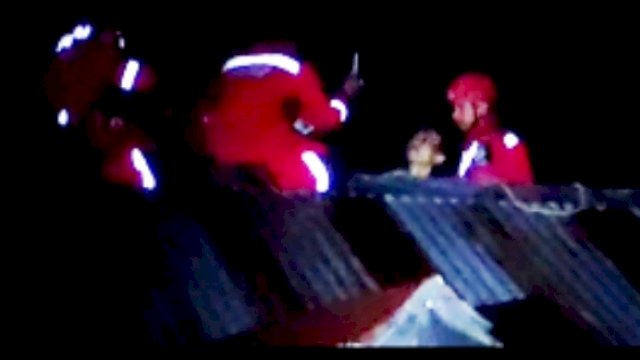 petugas Damkar Makassar yang sementara melakukan upaya penyelamatan seorang pria yang diduga hendak bunuh diri dari atas atap rumah warga. Foto: ist