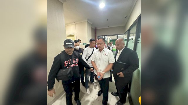 Polisi yang menggiring Helmut sambil kedua tangannya di ikat menggunakan tali ties. (Ist)