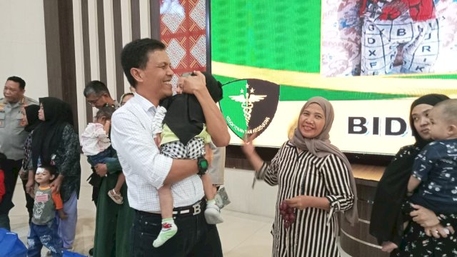 Dirreskrimsus Polda Sulsel, Kombes Pol Helmi Kwarta Kusuma Rauf yang menggendong salah satu balita yang dinyatakan stunting saat gelaran pemberian bantuan di Aula Mapolda Sulsel. Foto: Portalmedia.id/Reza