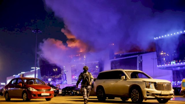 Seorang petugas penegak hukum Rusia berjalan di area parkir dekat tempat konser Balai Kota Crocus yang terbakar setelah insiden penembakan, di luar Moskow, Rusia, 22 Maret 2024. /Reuters/Maxim Shemetov
