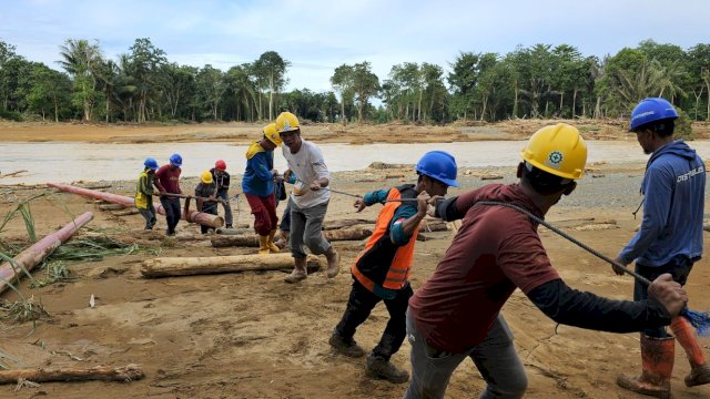 Akibat akses jembatan terputus, petugas PLN tengah berjibaku memobilisasi tiang melewati sungai ke Dusun Ajjilikeng, Kabupaten Wajo.