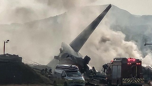 Pesawat Jeju Air jatuh di Bandara Internasional Muan, Provinsi Jeolla Selatan, Korea Selatan, Minggu (29/12/2024). Asap tampak membubung dari bangkai pesawat Boeing 737-800 ini. Sebanyak 47 korban tewas, dari total 181 orang di pesawat.(YONHAP via AFP)

