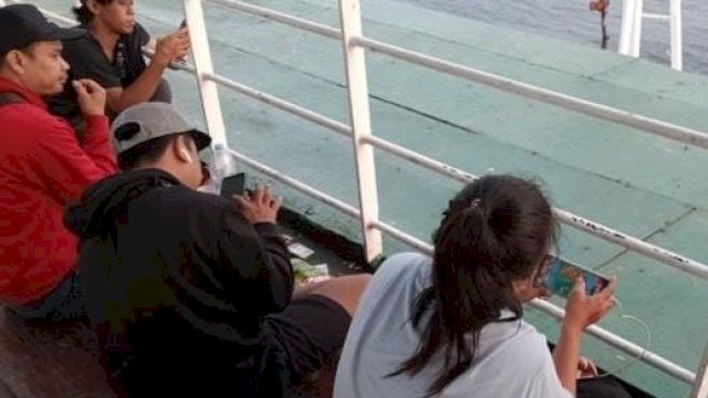 Sejumlah penumpang terlihat menggunakan ponsel saat kapal melaju di tengah laut. Akses jaringan telekomunikasi membuat mereka tetap terhubung selama perjalanan.