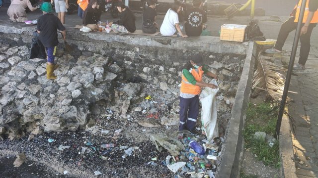 Petugas Satgas Kebersihan Kecamatan Ujung Pandang berjibaku mengumpulkan dan memasukkan sampah kiriman ke dalam karung di sekitar area tanggul batu Anjungan Pantai Losari, Jalan Penghibur, Kelurahan Maloku, Makassar.