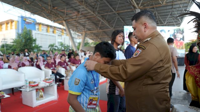 Wali Kota Makassar, Munafri Arifuddin, menyematkan atribut kepada perwakilan siswa saat membuka resmi O2SN tingkat SD/SMP dan GSI tingkat SMP se-Kota Makassar tahun 2026 di Lapangan Karebosi, Selasa (9/6/2026).
