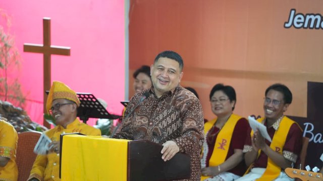 Wali Kota Makassar, Munafri Arifuddin, tampak menebar senyum hangat dari atas mimbar saat memberikan sambutan resmi mengenai penguatan toleransi dan iklim investasi kota pada Perayaan Paskah Jemaat Tello Batua yang dirangkaikan dengan Milad Gereja Toraja ke-79 di Makassar, Minggu (5/4/2026).