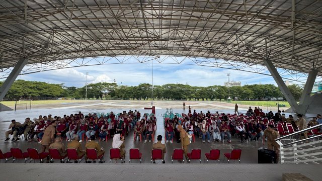 Camat Ujung Pandang, Nanin Sudiar A.P (berdiri, seragam dinas cokelat hijab), didampingi Sekcam dan jajaran lurah saat memimpin rapat koordinasi penguatan komitmen persampahan bersama seluruh elemen Ketua RT/RW se-Kecamatan Ujung Pandang di bawah struktur atap tribun Lapangan Karebosi, Makassar, Selasa (7/4/2026).