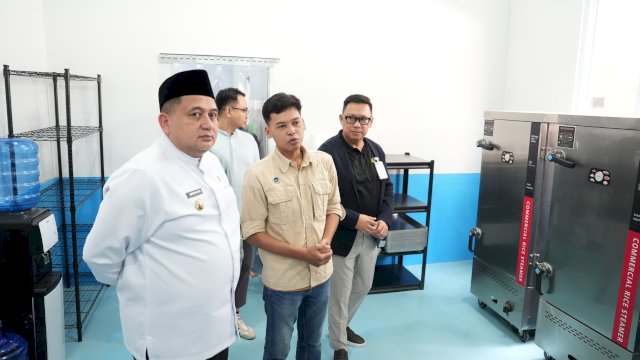 Wali Kota Makassar, Munafri Arifuddin (kiri, berpakaian dinas putih), saat melakukan peninjauan langsung fasilitas mesin pengolah pangan modern di dalam ruang dapur Satuan Pelayanan Pemenuhan Gizi (SPPG) Manggala 03, Jalan Antang Raya, Makassar, Jumat (10/4/2026). Kehadiran SPPG yang dikelola Yayasan Wadah Merah Putih dari Wahdah Islamiyah ini diharapkan mampu memperkuat ekosistem Program Makan Bergizi Gratis (MBG) sekaligus menggerakkan roda ekonomi pasar tradisional lewat penyerapan bahan baku
