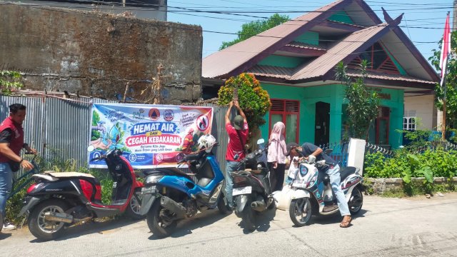 Tim KALTANA Kaluku Bodoa memasang spanduk sosialisasi imbauan hemat air dan pencegahan kebakaran bantuan PLN UIP Sulawesi di Makassar, Minggu (13/9/2026).